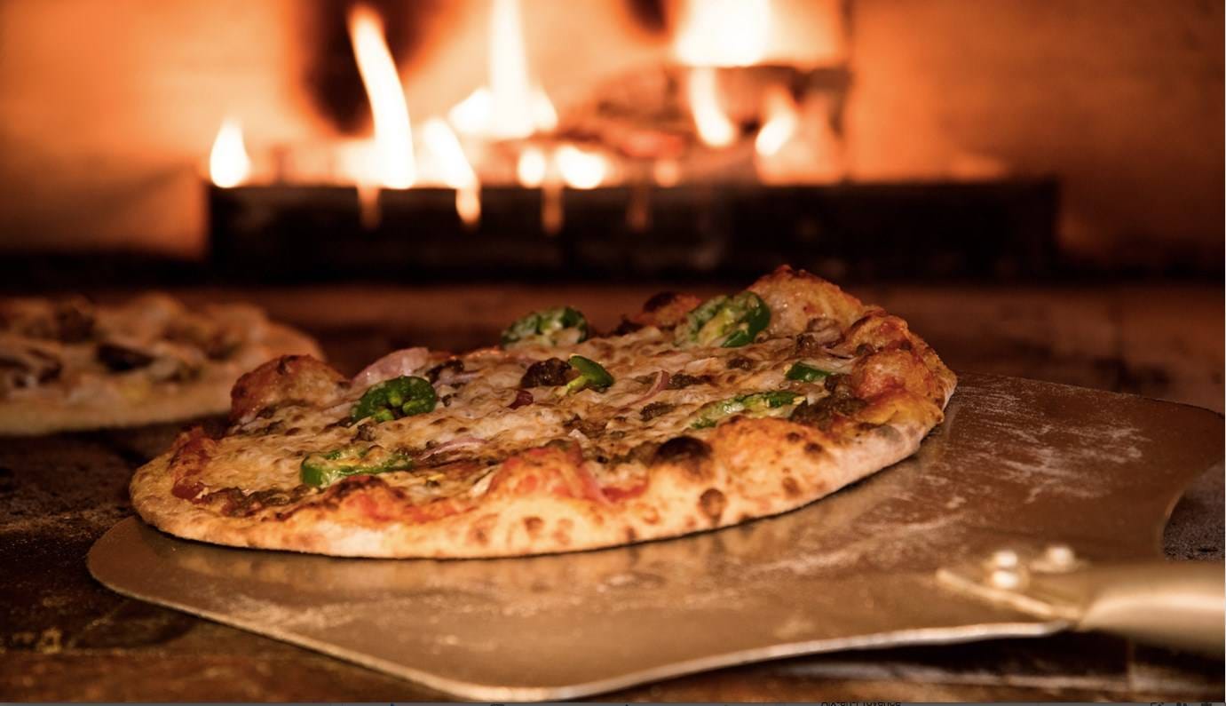 Pizza qui sort du four à feu de bois